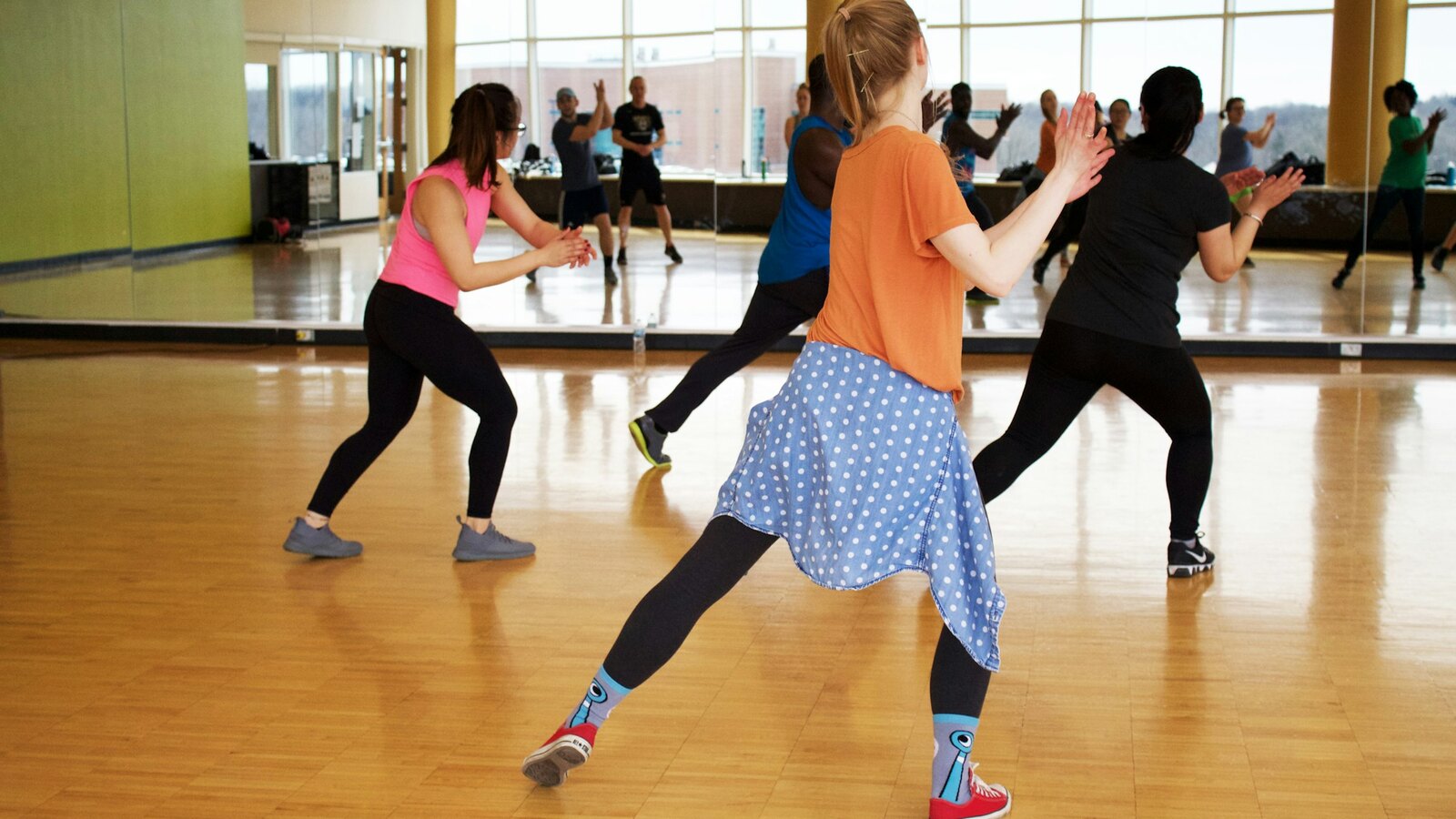 A dance studio with a wooden floor and large windows