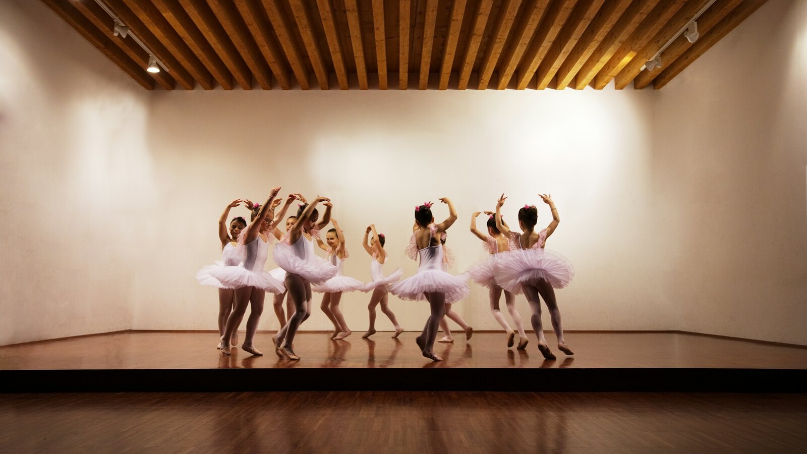 A group of young dancers mid movement in a bright studio