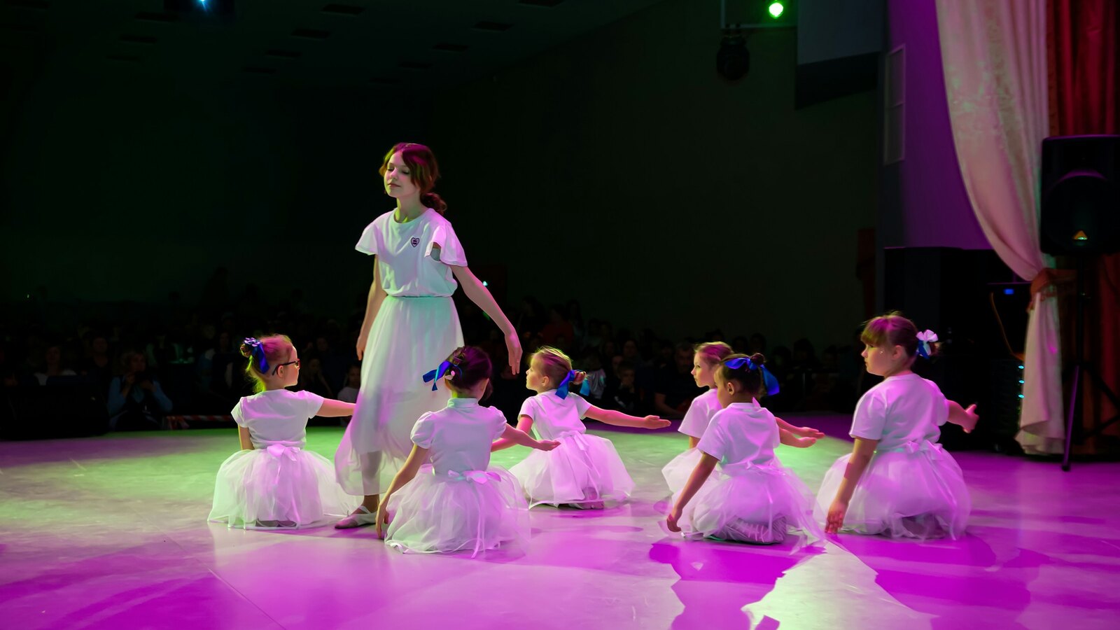 Children performing on a theatre stage under warm lights